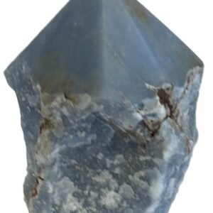 Natural rough angelite freeform crystal with unpolished sides and a smooth polished blue point standing on a white background